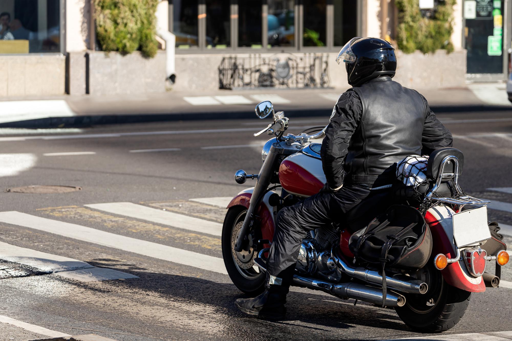Helmeted motorcyclist riding through a city street in Sacramento, California