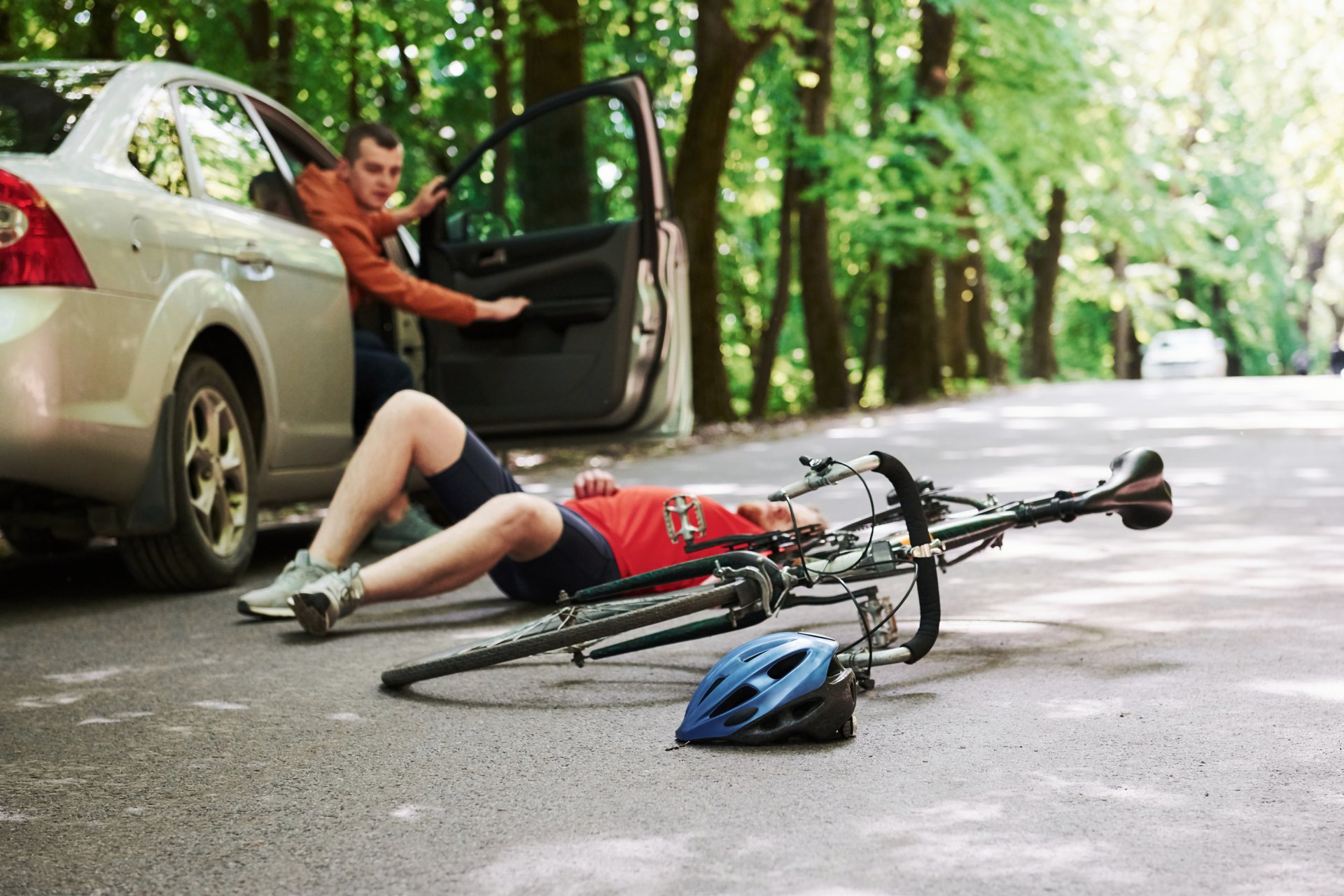 Injured cyclist on the road beside a car after a Roseville bicycle accident